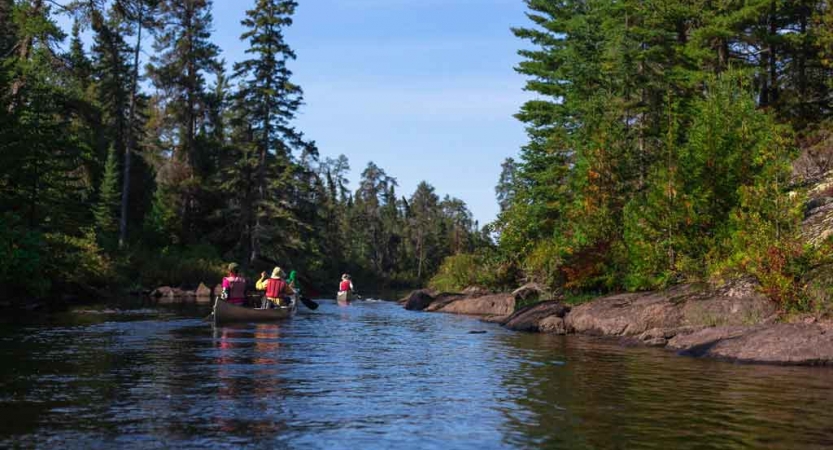 two kayaks are paddled on a calm river that flows between trees on an outward bound gap year semester